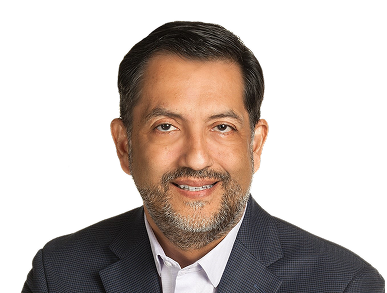Head-and-shoulders portrait of a smiling man in a dark blazer and white shirt.